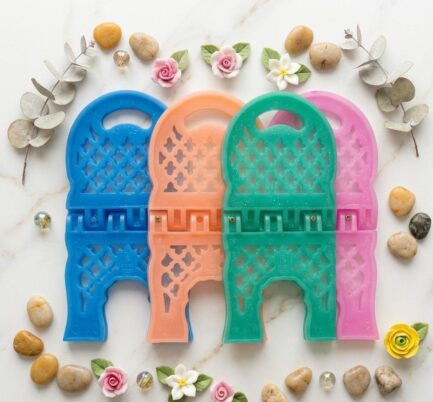 Colorful silicone Rehal resin molds in blue, peach, green, and pink displayed with decorative flowers and stones on a marble background.